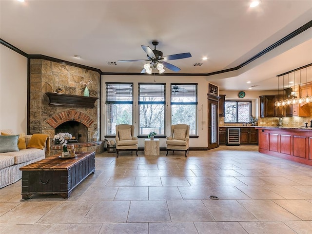 living room featuring ornamental molding, ceiling fan, wine cooler, and a fireplace