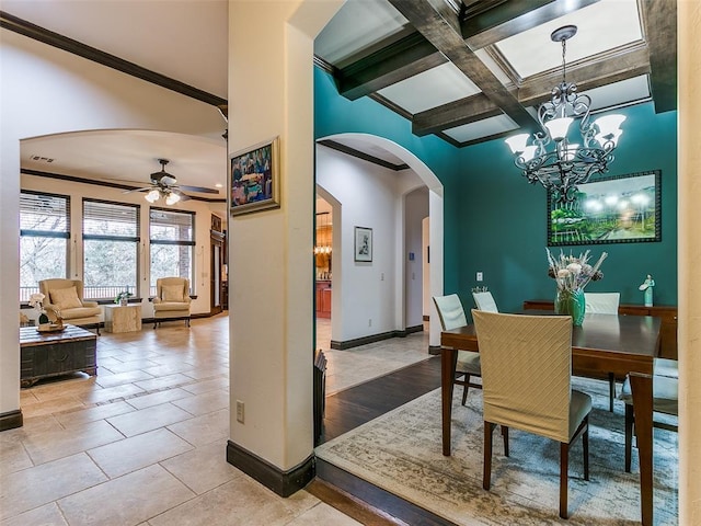 dining area with light tile patterned floors, coffered ceiling, ornamental molding, ceiling fan with notable chandelier, and beamed ceiling