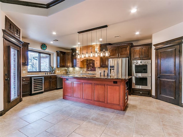 kitchen featuring pendant lighting, tasteful backsplash, beverage cooler, a center island, and stainless steel appliances