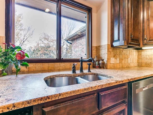 kitchen featuring stainless steel dishwasher, light stone countertops, sink, and decorative backsplash