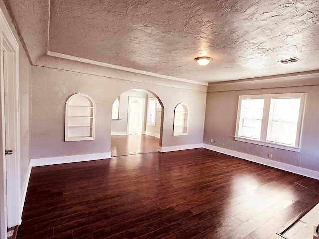 spare room featuring a textured ceiling and dark wood-type flooring