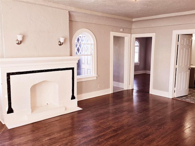 unfurnished living room with plenty of natural light, dark hardwood / wood-style flooring, a textured ceiling, and a brick fireplace