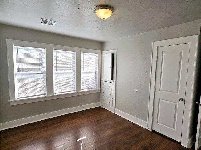 unfurnished bedroom with dark hardwood / wood-style flooring and multiple windows