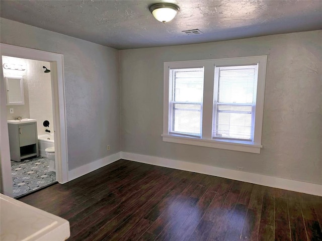 spare room with a textured ceiling, dark hardwood / wood-style flooring, and sink