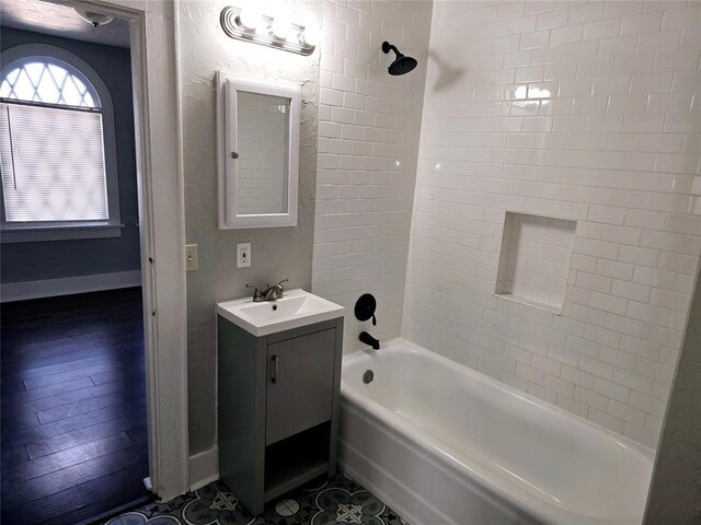 bathroom with hardwood / wood-style floors, vanity, and tiled shower / bath