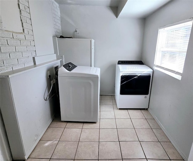 laundry area with washing machine and clothes dryer and light tile patterned floors