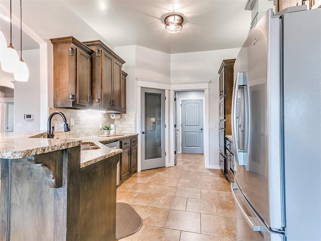 kitchen with pendant lighting, a breakfast bar area, light stone countertops, tasteful backsplash, and stainless steel appliances