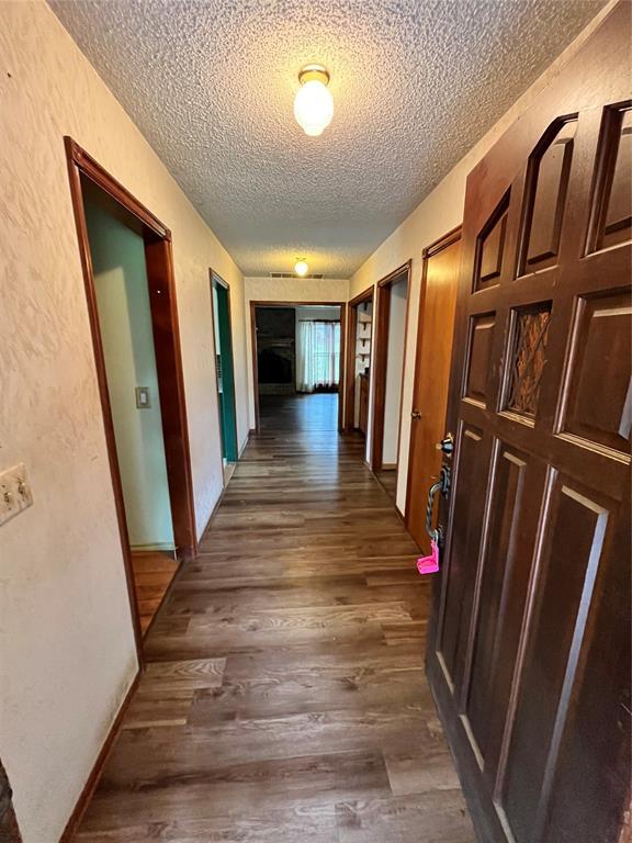 15268 Pheasant Run, Choctaw, OK 73020 - hall featuring a textured ceiling, dark wood-type flooring, and a textured wall