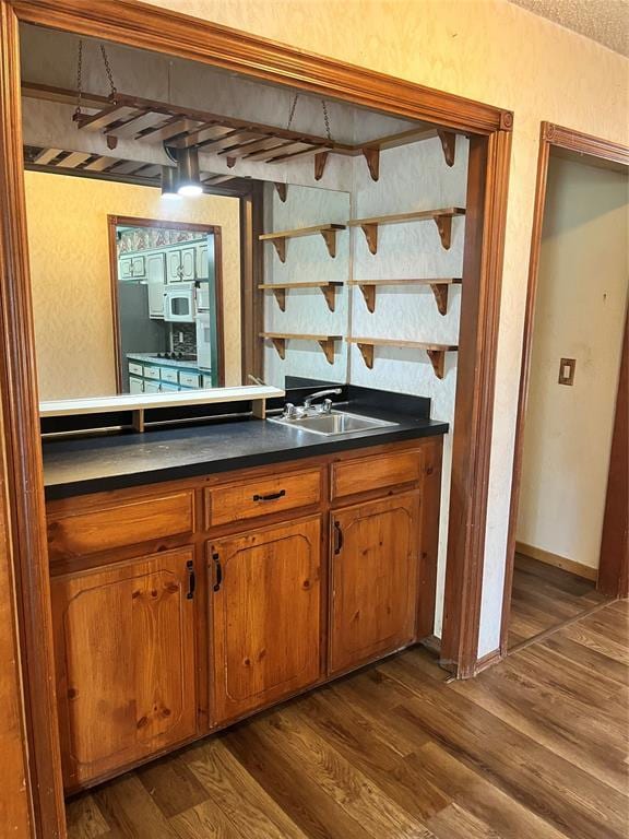 15268 Pheasant Run, Choctaw, OK 73020 - bar featuring white microwave, a sink, dark wood-type flooring, and a textured wall