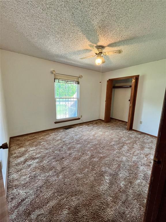 15268 Pheasant Run, Choctaw, OK 73020 - unfurnished bedroom with a textured ceiling, carpet, and ceiling fan