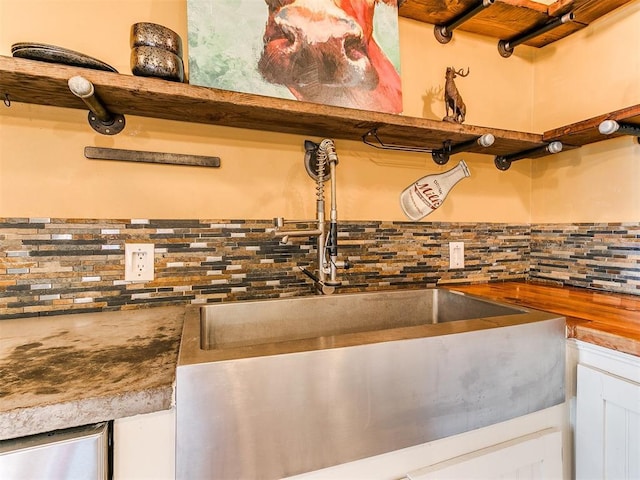 room details featuring decorative backsplash, white cabinets, and sink