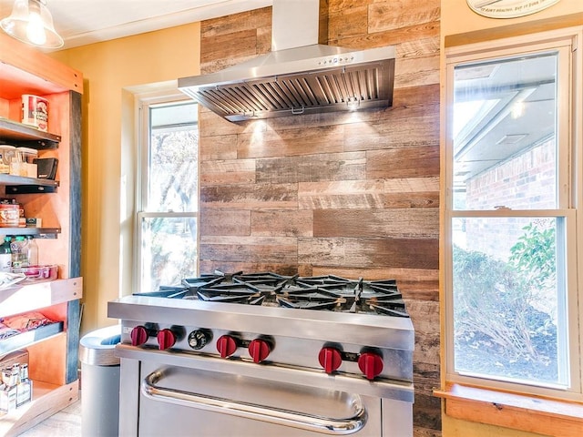 kitchen featuring high end range, wall chimney exhaust hood, and wood walls