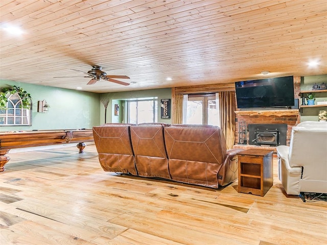 living room featuring wooden ceiling, a wood stove, and light hardwood / wood-style flooring