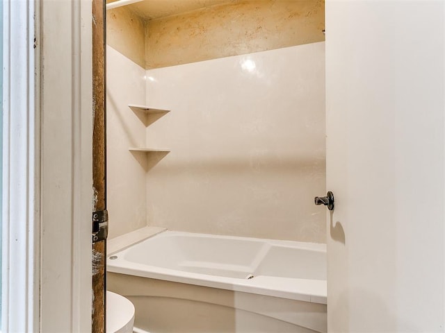 bathroom with a tub to relax in and toilet