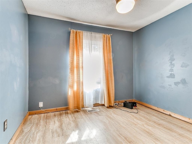 empty room featuring hardwood / wood-style flooring and a textured ceiling