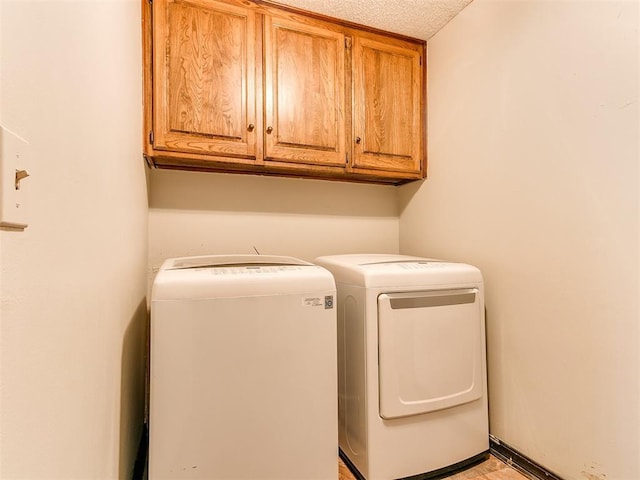 washroom featuring washer and dryer, cabinets, and a textured ceiling