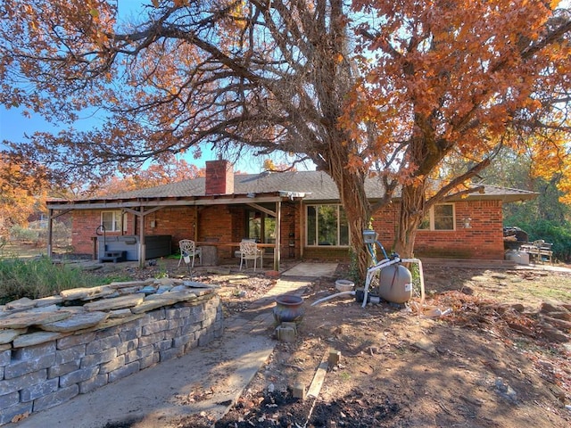 rear view of house featuring a patio area and a hot tub