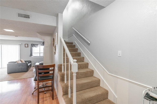 stairs with a textured ceiling and hardwood / wood-style flooring