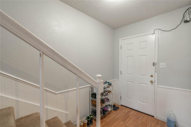 foyer entrance with light hardwood / wood-style floors and a textured ceiling