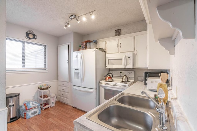 kitchen with light wood-type flooring, a textured ceiling, white appliances, sink, and white cabinets