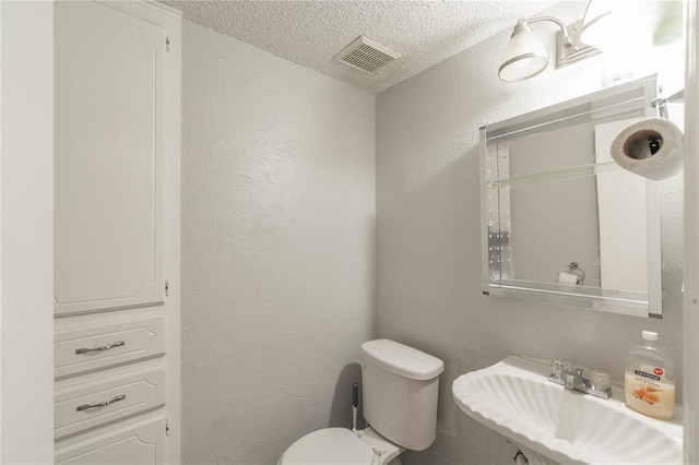 bathroom featuring sink, a textured ceiling, and toilet