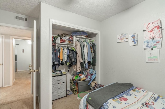 bedroom with light carpet, a textured ceiling, and a closet