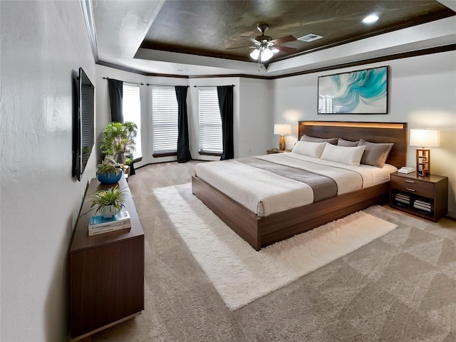 carpeted bedroom featuring ceiling fan, ornamental molding, and a tray ceiling