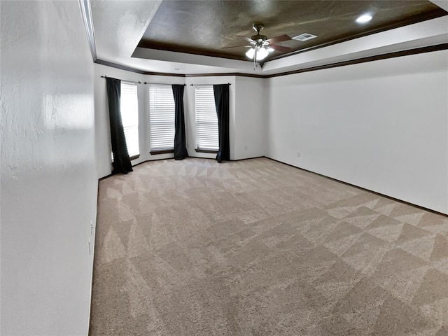 unfurnished room featuring a tray ceiling, ceiling fan, light colored carpet, and ornamental molding