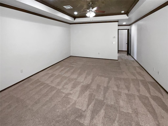 carpeted empty room with a raised ceiling, ceiling fan, and ornamental molding