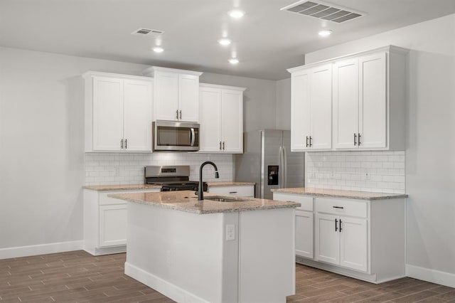 kitchen featuring white cabinets, stainless steel appliances, a center island with sink, and sink