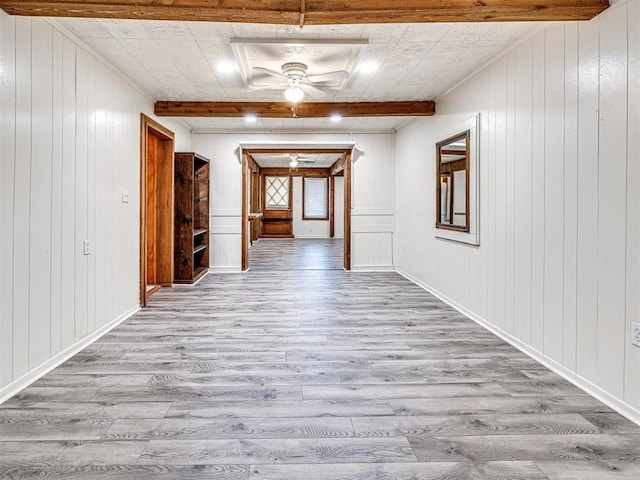 corridor featuring beamed ceiling, wooden walls, and light hardwood / wood-style flooring