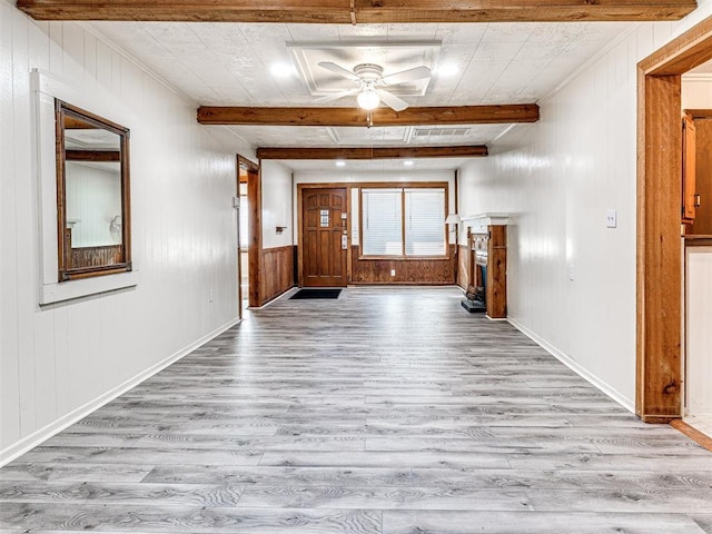 interior space with beamed ceiling, light wood-type flooring, ceiling fan, and wood walls