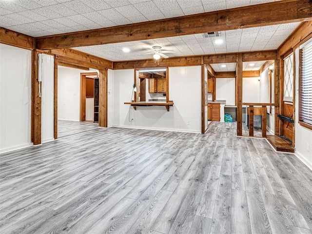 unfurnished living room featuring wood walls, ceiling fan, and light hardwood / wood-style floors