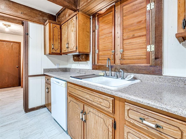 kitchen with white dishwasher, wood walls, and sink