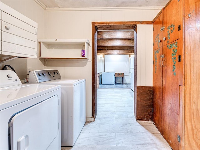 clothes washing area with washer and clothes dryer, wood walls, and crown molding