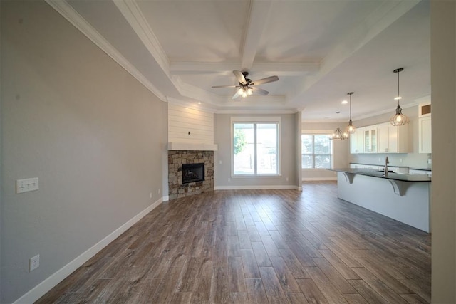 unfurnished living room featuring ceiling fan, ornamental molding, a fireplace, and dark wood-type flooring