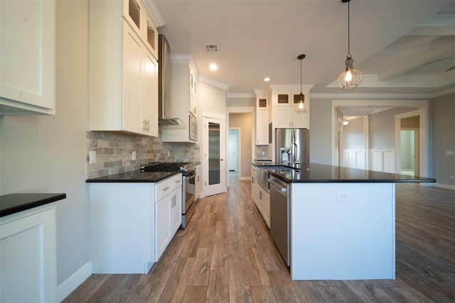 kitchen featuring white cabinetry, an island with sink, pendant lighting, appliances with stainless steel finishes, and ornamental molding