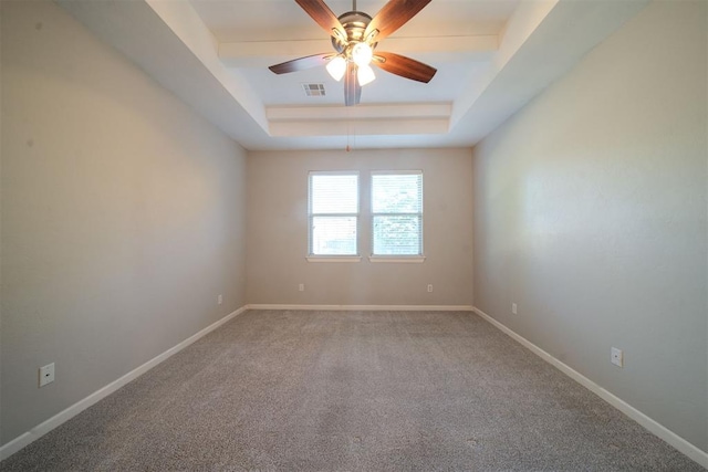 carpeted spare room with a tray ceiling and ceiling fan