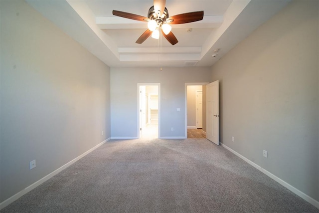 carpeted spare room featuring a tray ceiling and ceiling fan