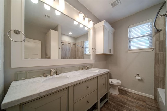 full bathroom featuring wood-type flooring, vanity, toilet, and tiled shower / bath combo