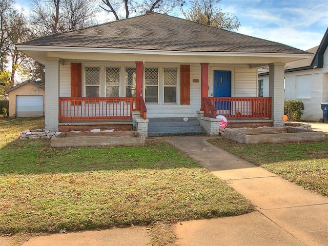 bungalow featuring a porch, a front lawn, an outdoor structure, and a garage