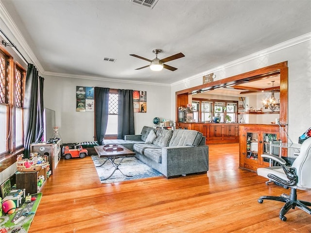 living room with ceiling fan with notable chandelier, wood-type flooring, and crown molding