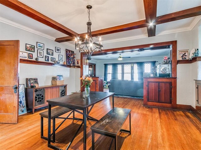 dining space with light wood-type flooring, ornamental molding, coffered ceiling, ceiling fan with notable chandelier, and beamed ceiling