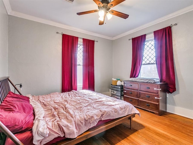 bedroom featuring ceiling fan, light wood-type flooring, crown molding, and multiple windows