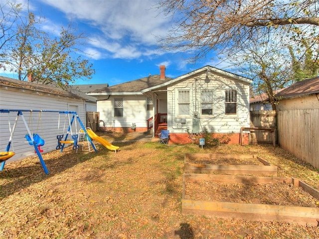 rear view of property with a playground