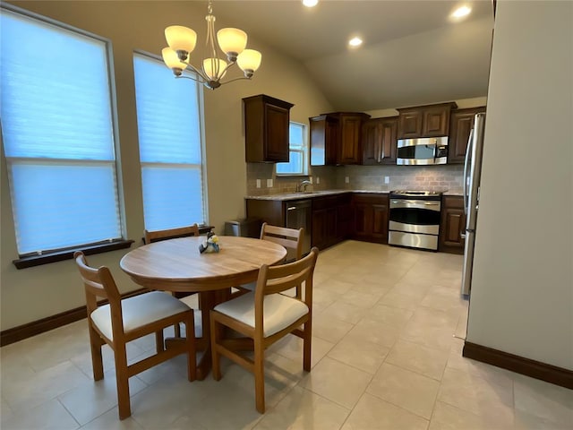 kitchen with lofted ceiling, sink, appliances with stainless steel finishes, decorative light fixtures, and a chandelier