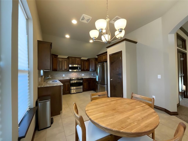 kitchen with decorative backsplash, appliances with stainless steel finishes, decorative light fixtures, a notable chandelier, and lofted ceiling