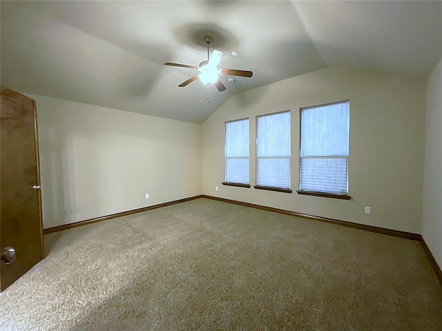 carpeted spare room featuring vaulted ceiling and ceiling fan