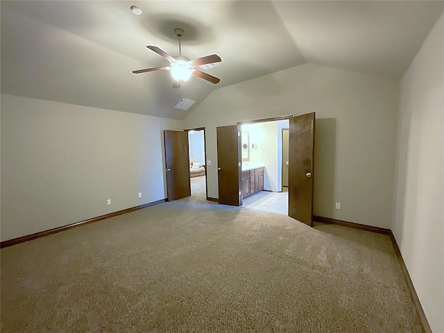 unfurnished bedroom featuring ensuite bath, ceiling fan, light colored carpet, and lofted ceiling