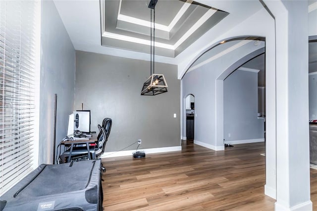 exercise area with ornamental molding, hardwood / wood-style flooring, and a tray ceiling